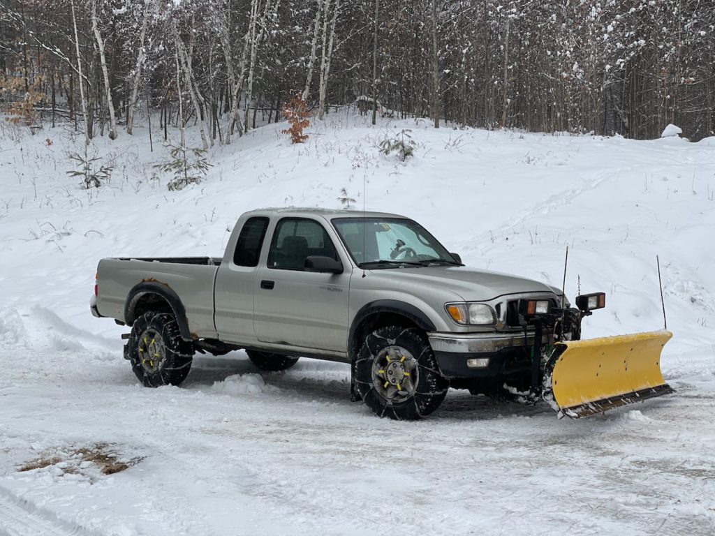 Side view of the 2003 Tacoma with its plow and chains on from January 2021.